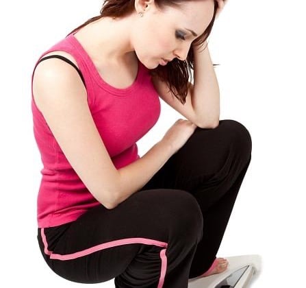 Close crop of a woman on a scale, representing the emotional pressure behind weight-loss timeline searches.
