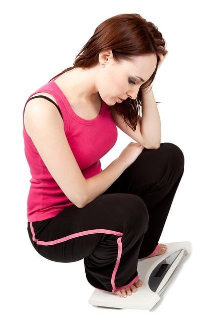 Woman standing on a scale while feeling frustrated that progress is not happening fast enough.